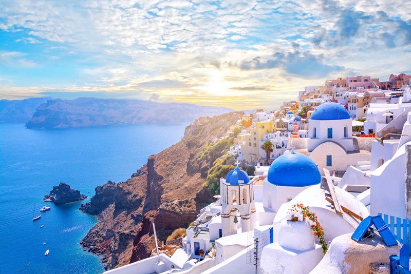 Beautiful Oia town on Santorini island, Greece. Traditional white architecture and greek orthodox churches with blue domes over the Caldera, Aegean sea